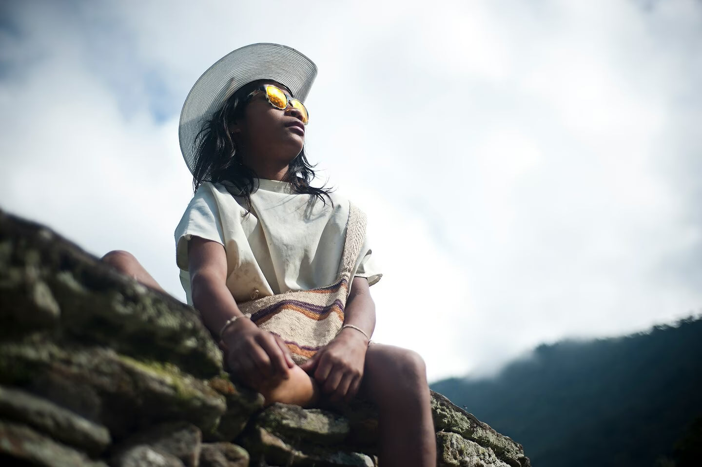 A little girl wearing sunglasses looks up