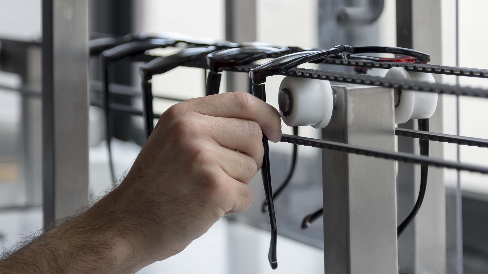 This is an industrial overhead conveyor system used for manufacturing or organizing eyewear.